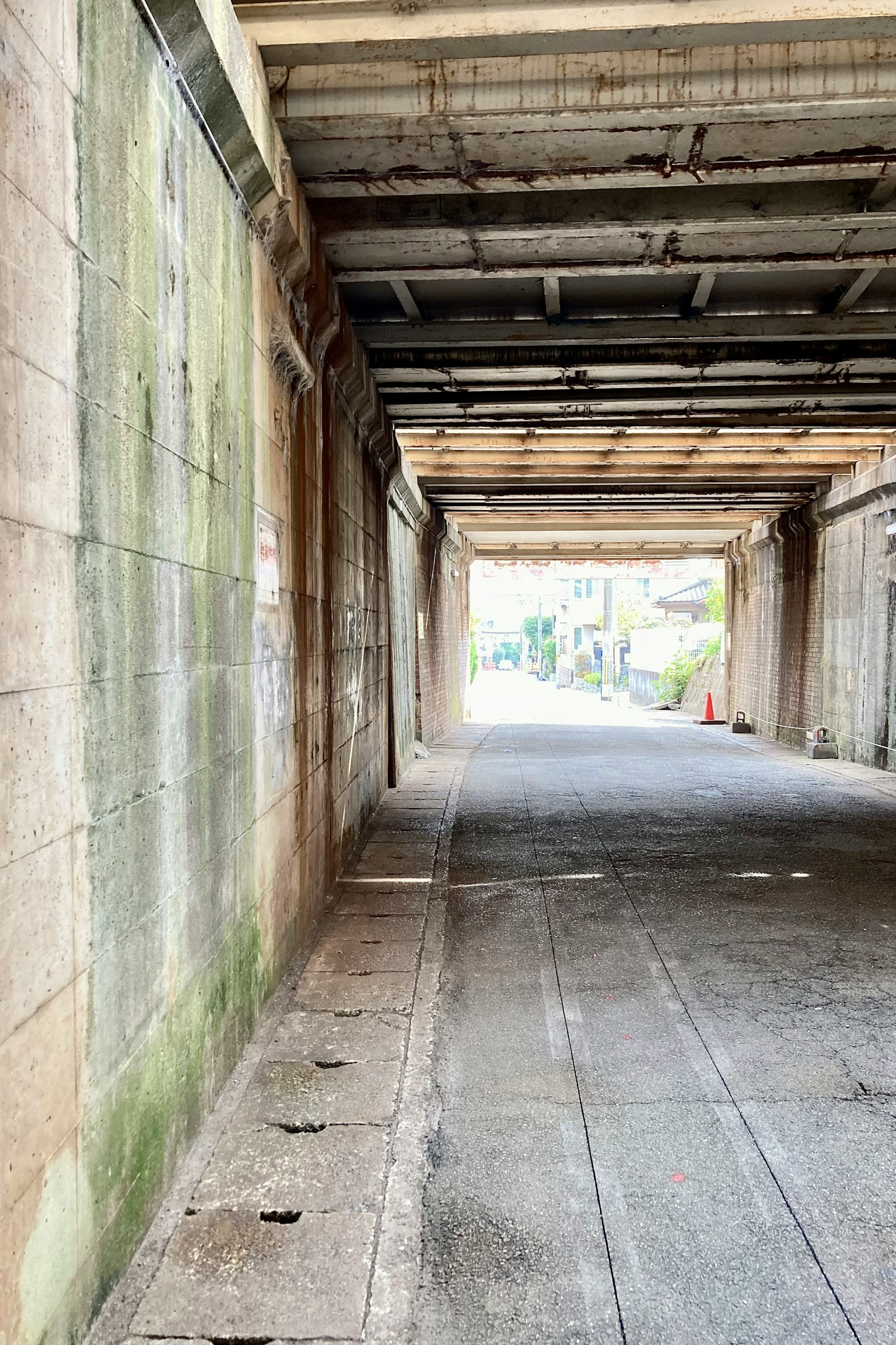 A corridor of an old arcade featuring concrete walls and a wooden ceiling
