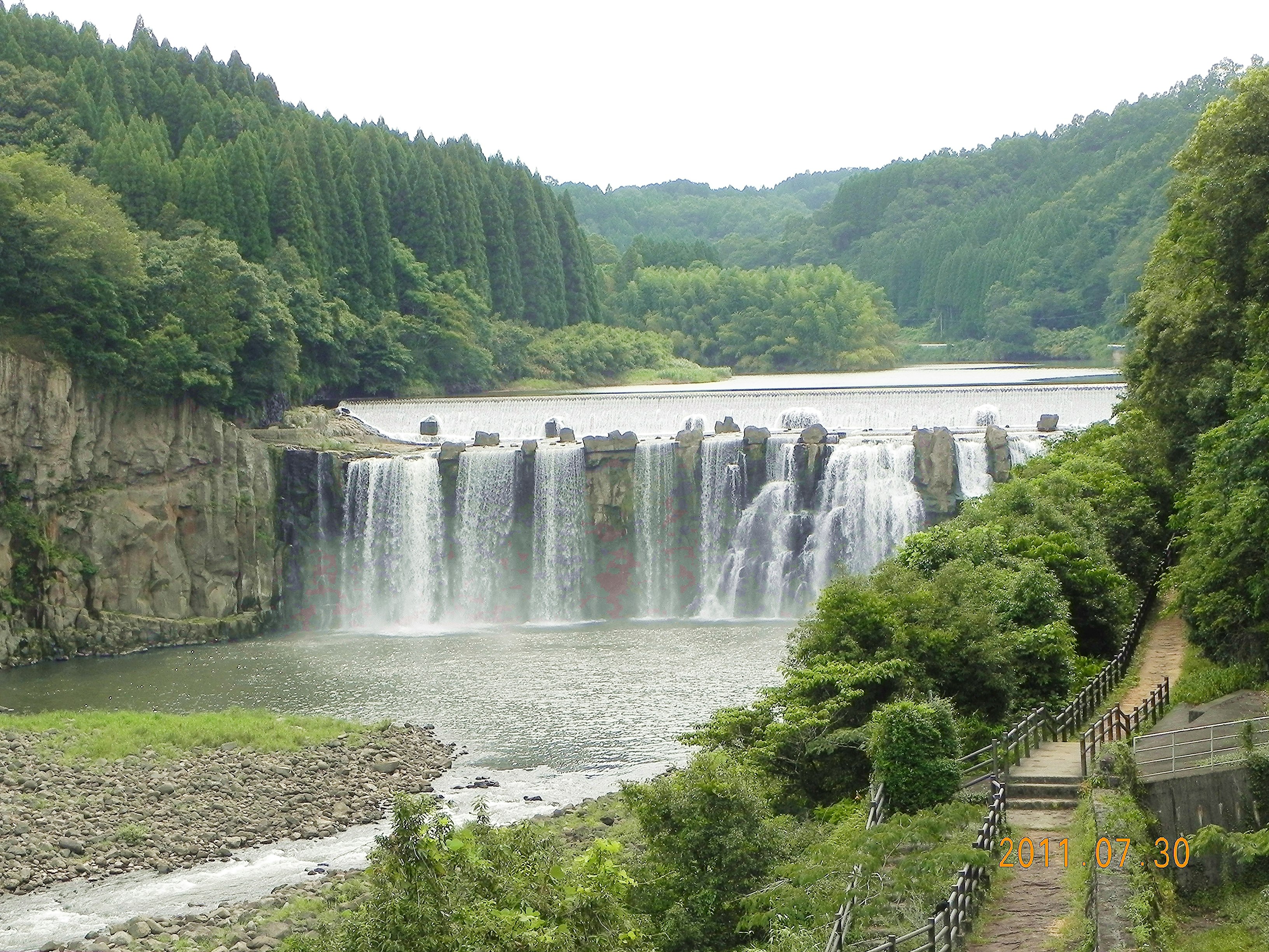 緑の渓谷に広がる滝とダムの水面