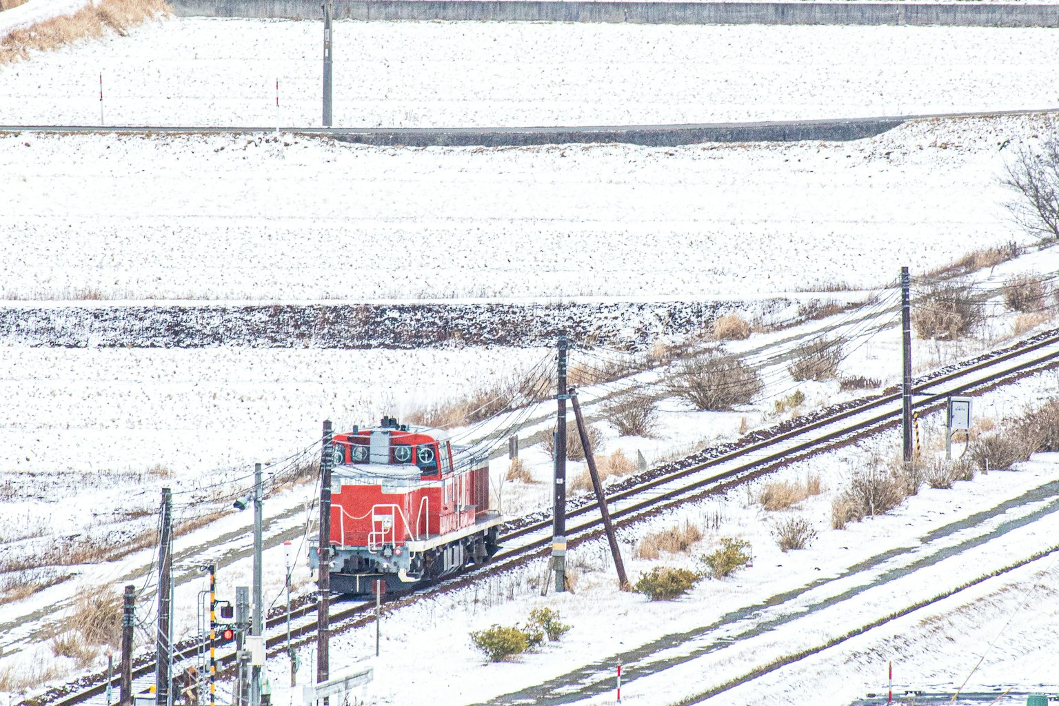 Locomotiva rossa che corre su binari coperti di neve