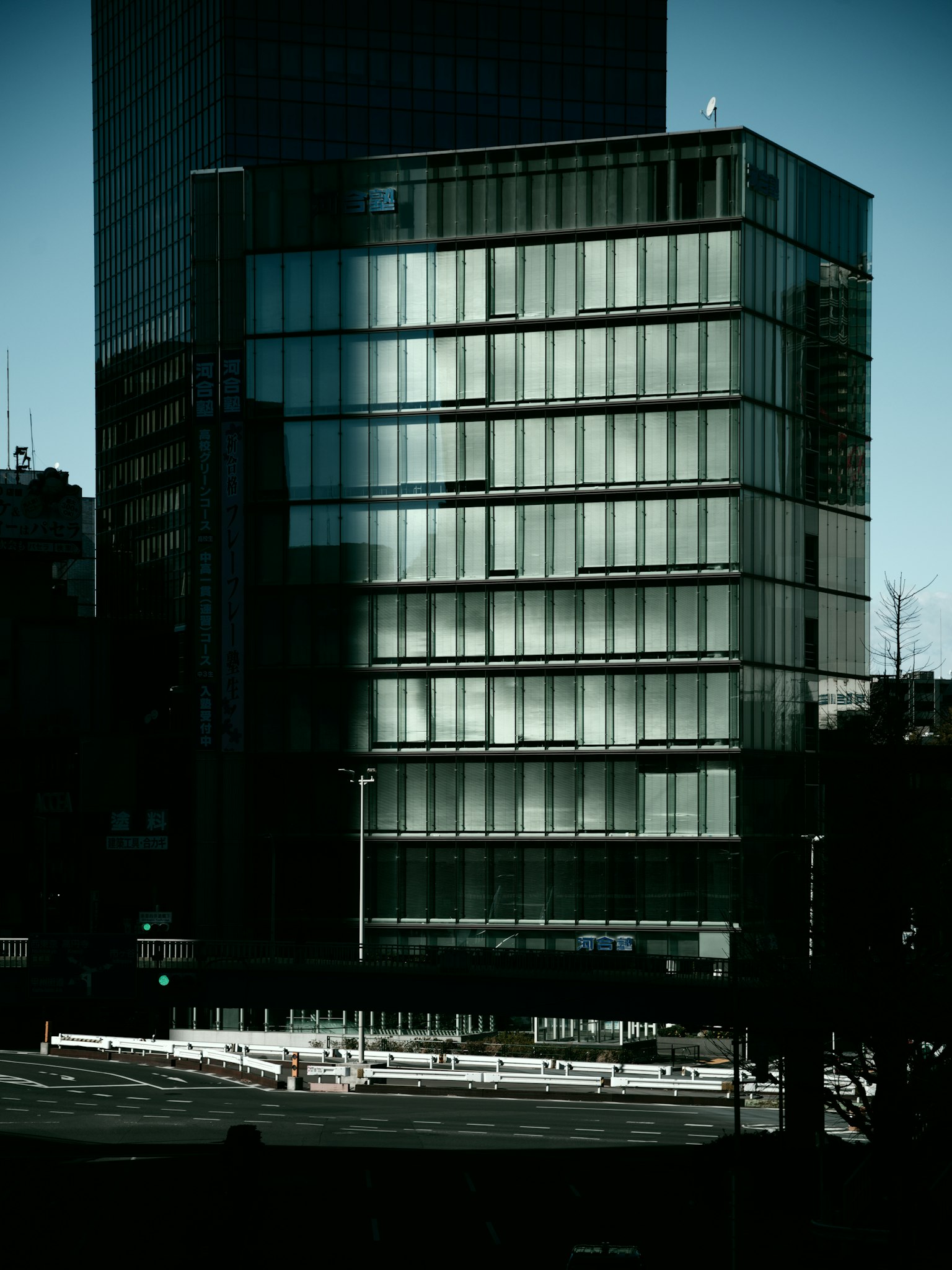 現代玻璃建築在陰影中，背景為城市