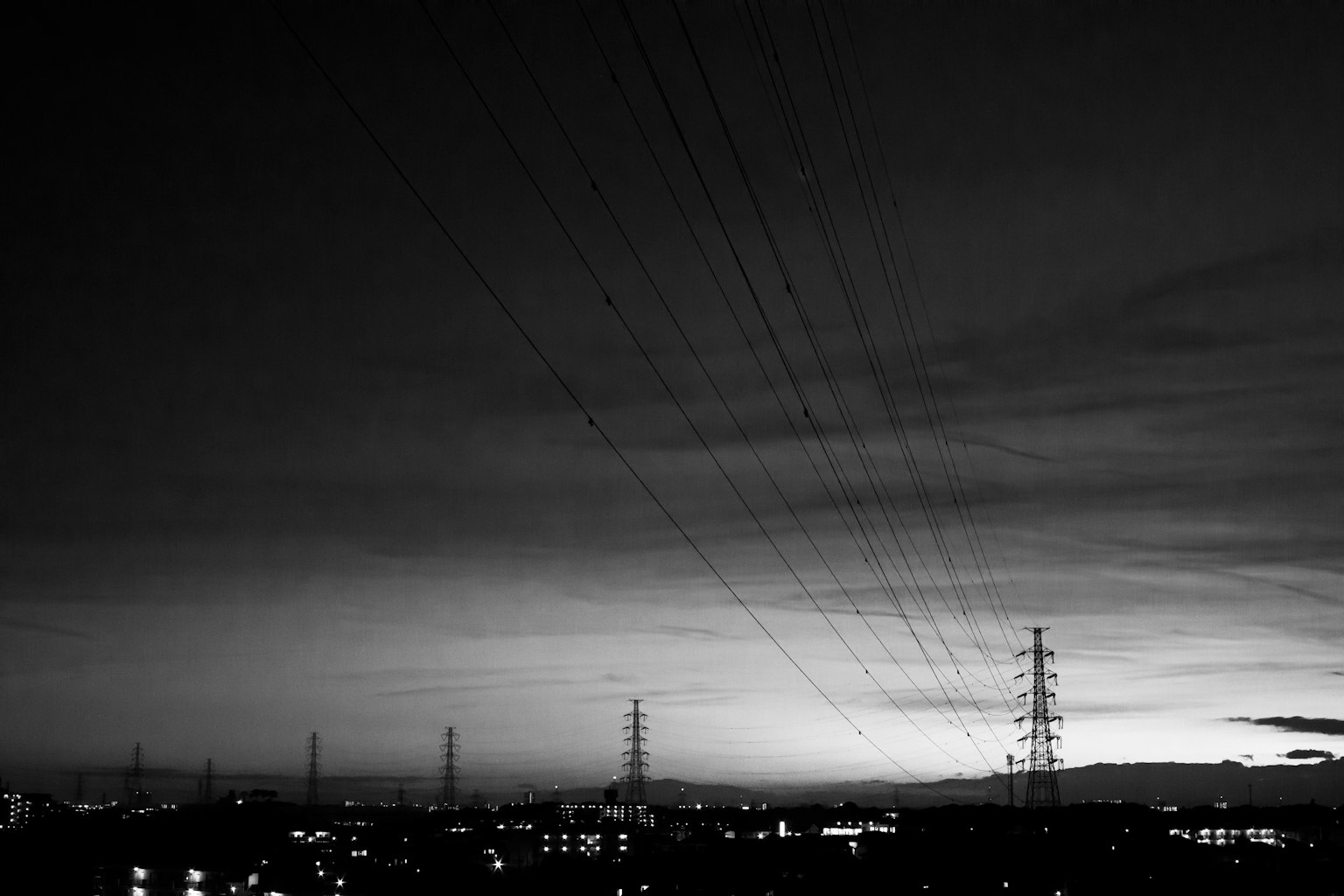 Silhouettes de lignes électriques et de bâtiments contre un ciel crépusculaire