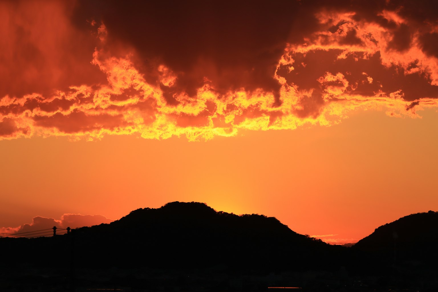 夕焼けの山のシルエットとオレンジ色の空