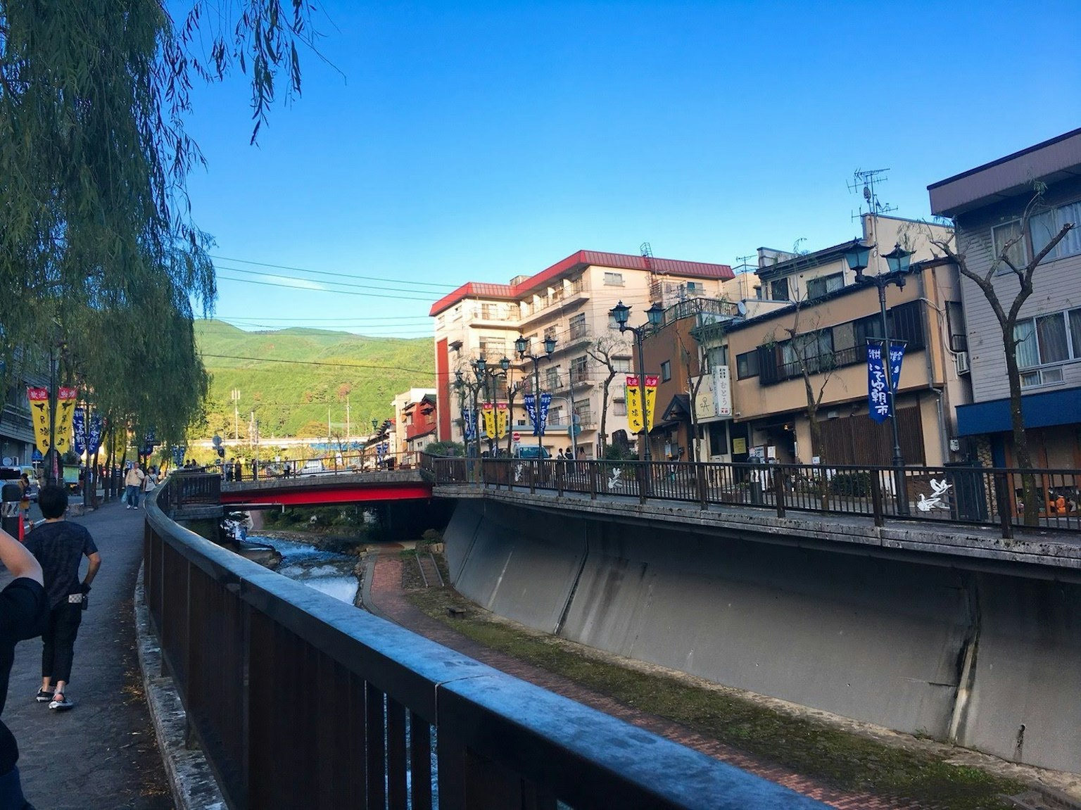 Vue pittoresque au bord de la rivière avec un pont rouge et des boutiques