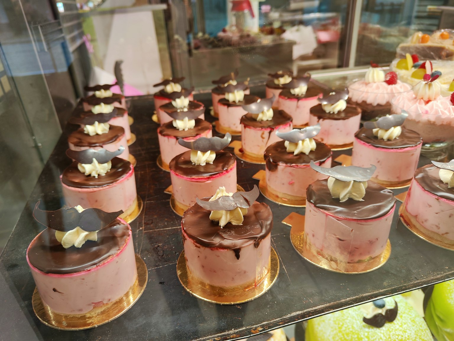 Etalase kue merah muda yang dihiasi krim dan cokelat