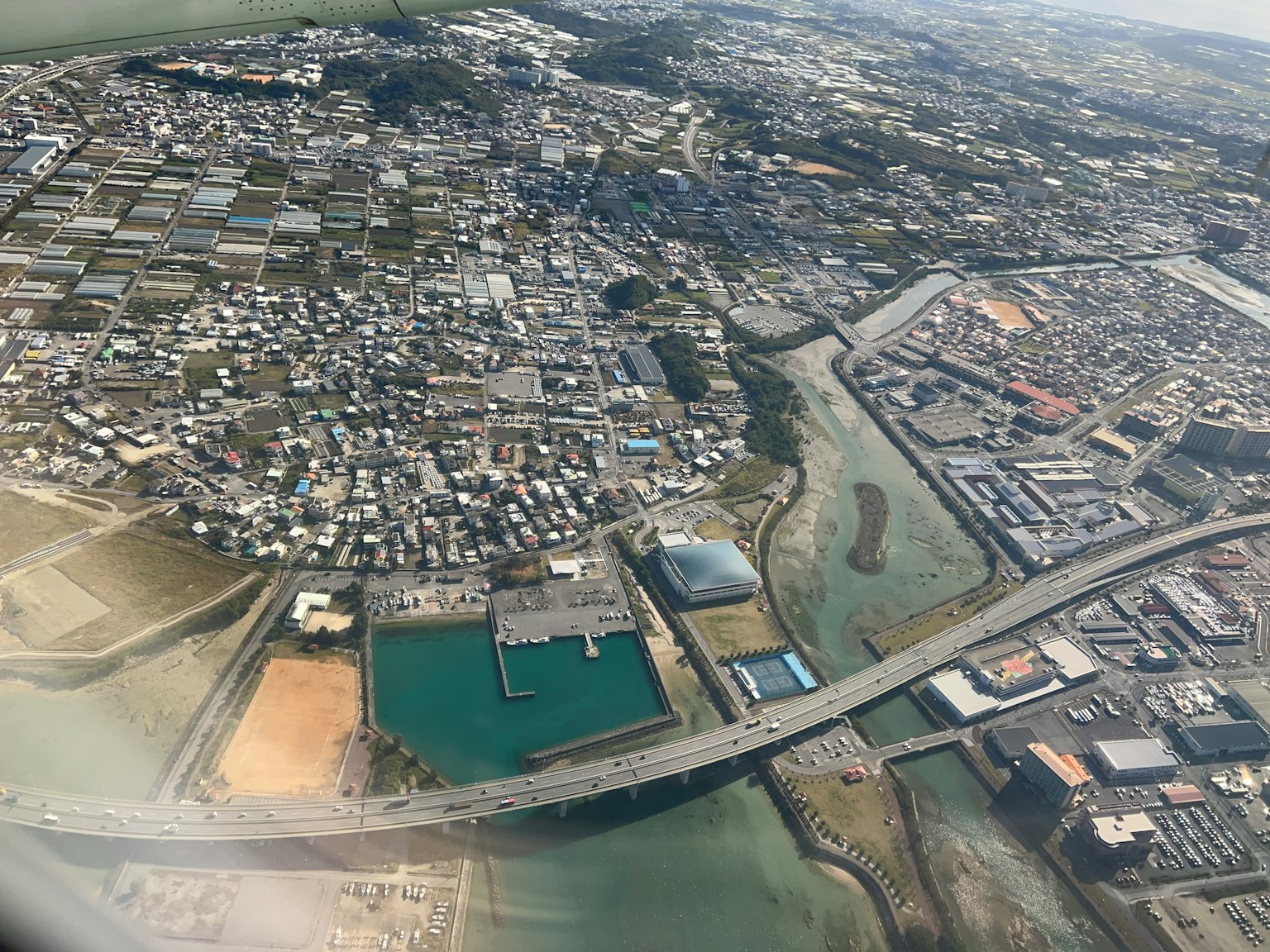 Vista aérea de una ciudad y cuerpos de agua con un puente y áreas de agua verde