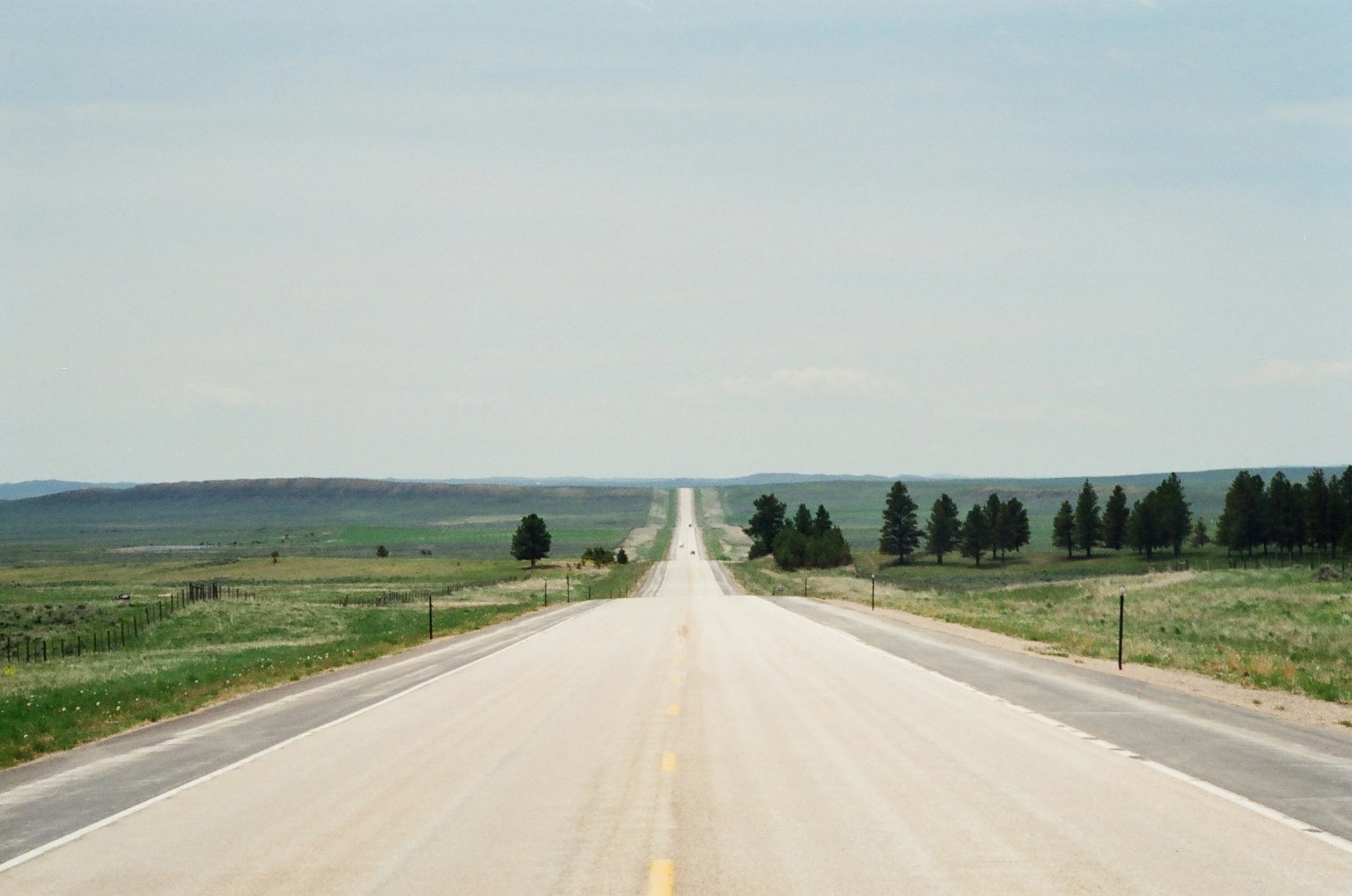 Straight road through expansive grassland under a clear sky