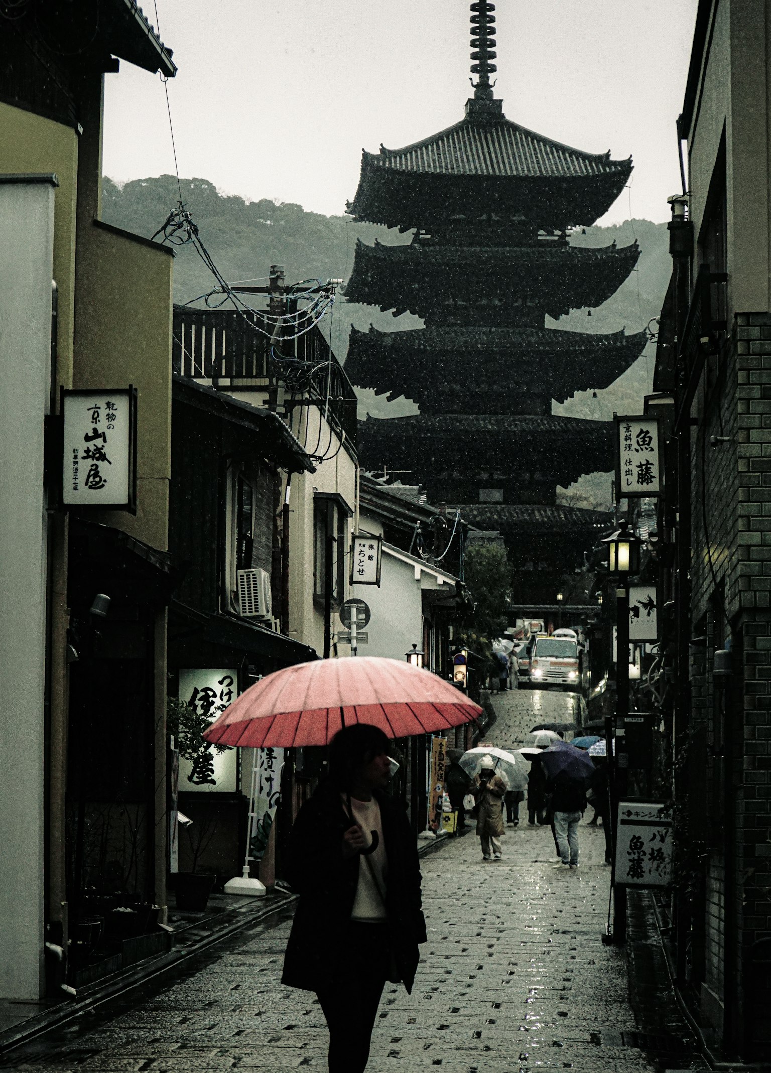 在雨中拿著紅傘走近塔樓的人