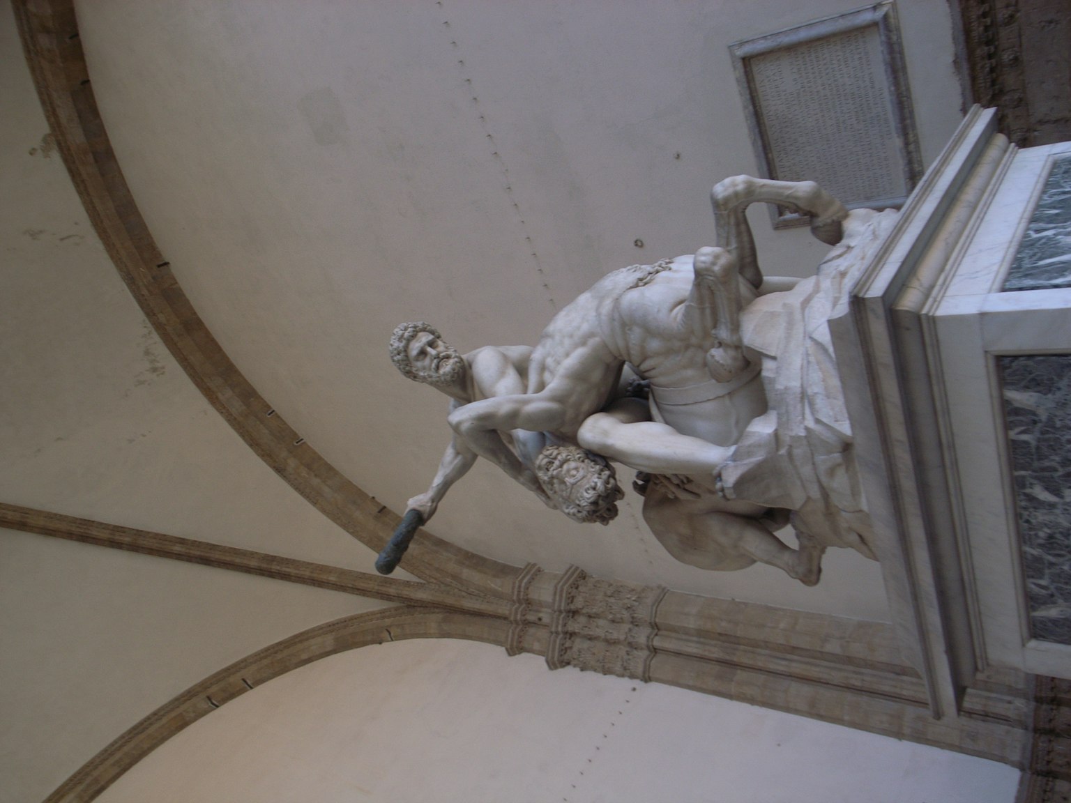 Una escultura de un hombre sosteniendo a una mujer con un techo arqueado al fondo