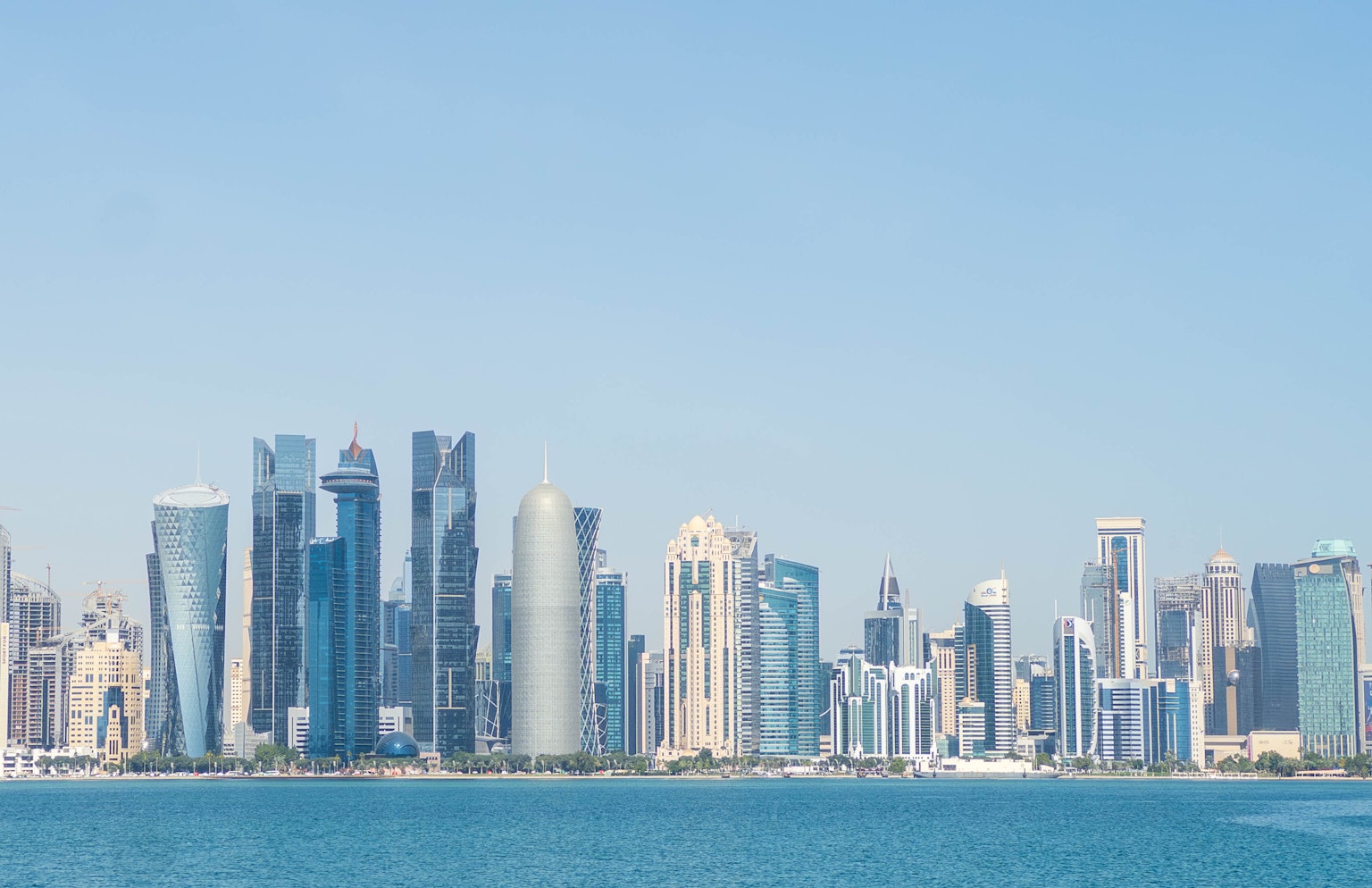 Garis langit Doha dengan gedung pencakar langit modern di latar belakang langit biru dan laut