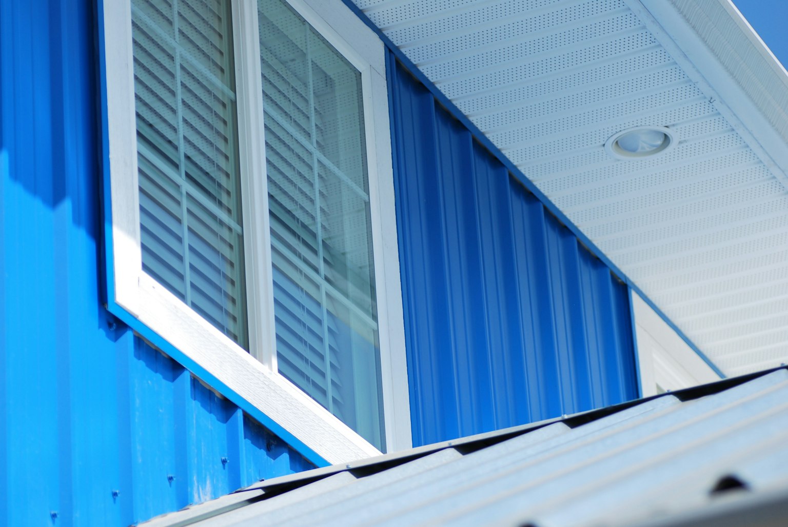 Close-up of a blue metal wall with a white window frame