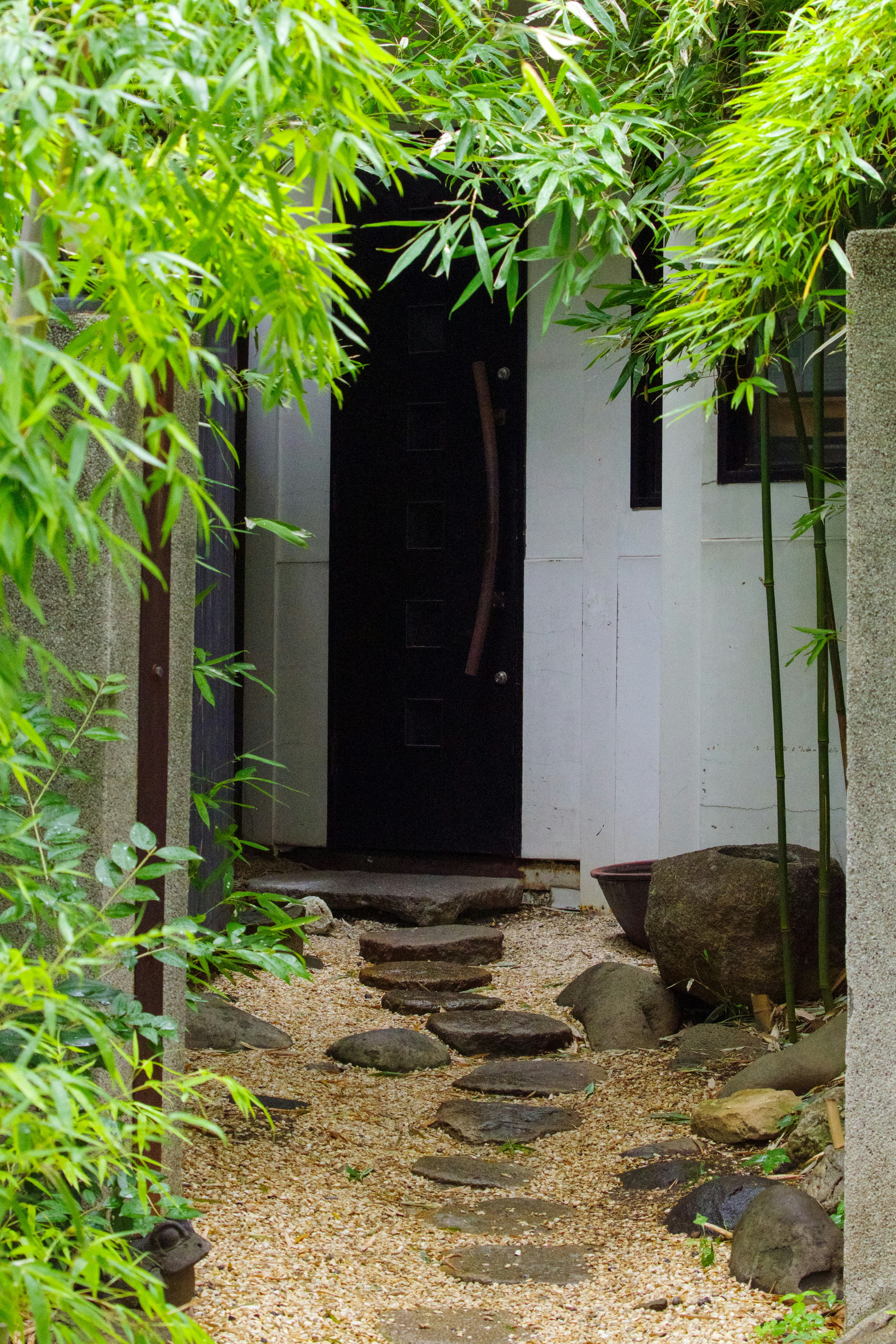 Stone-paved garden path framed by bamboo and a courtyard entrance