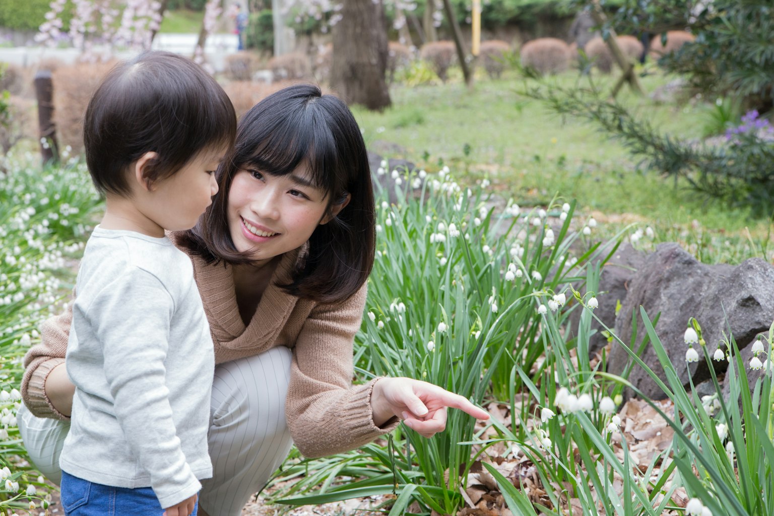 女人在公园里指着花朵与孩子互动
