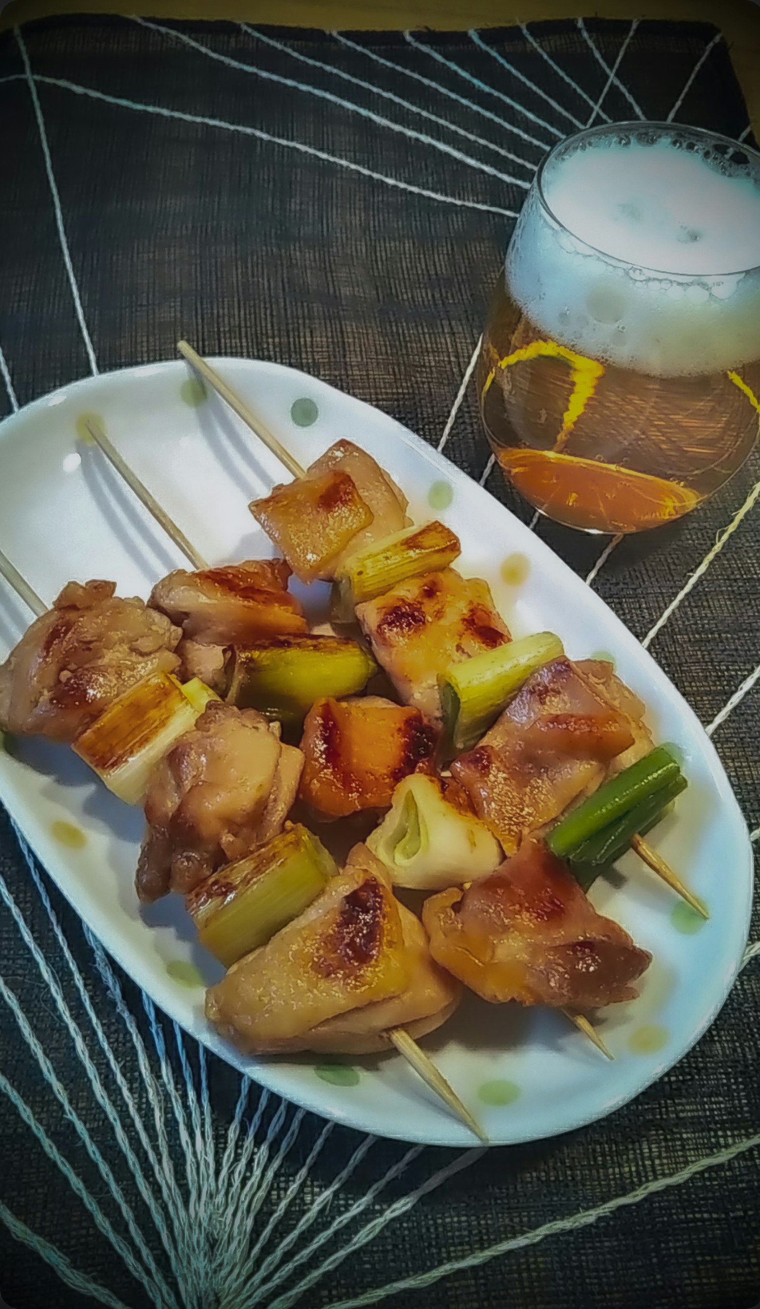Plato de brochetas de carne y verduras servido con cerveza