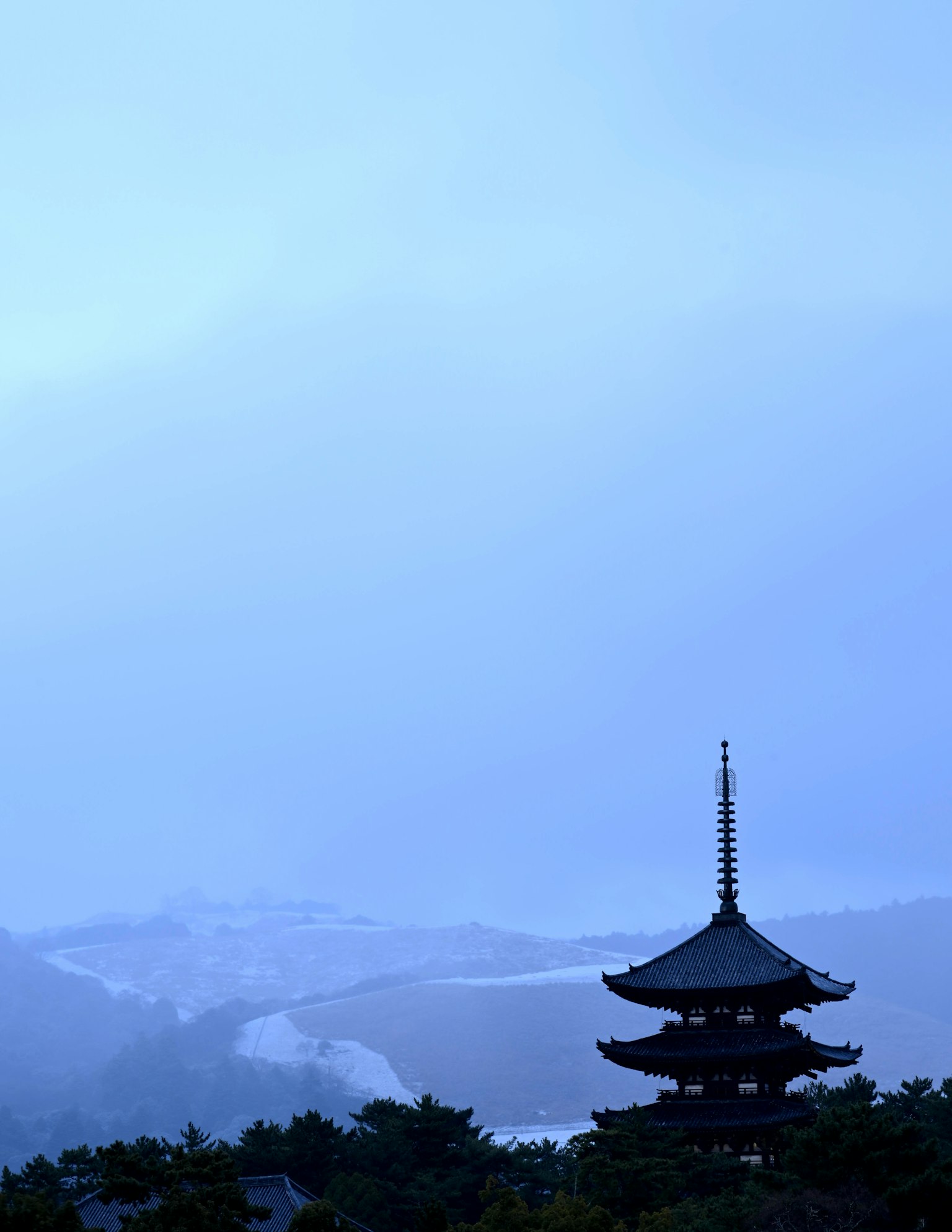 蓝天背景下的塔楼剪影与被雪覆盖的丘陵