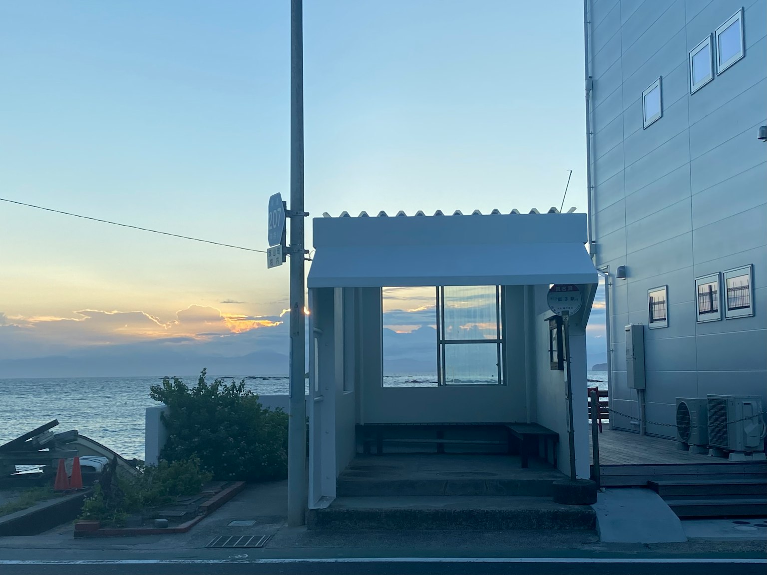 Una semplice fermata dell'autobus vicino al mare con un edificio sullo sfondo