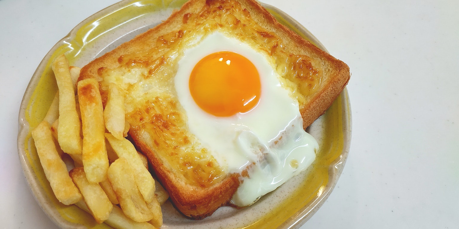 Plate of toasted bread with a fried egg and French fries