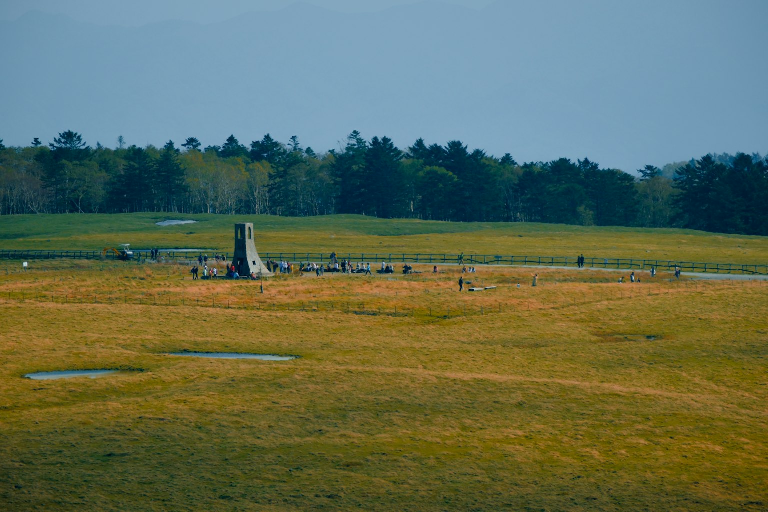 広大な草原に立つモニュメントと訪れる人々の風景