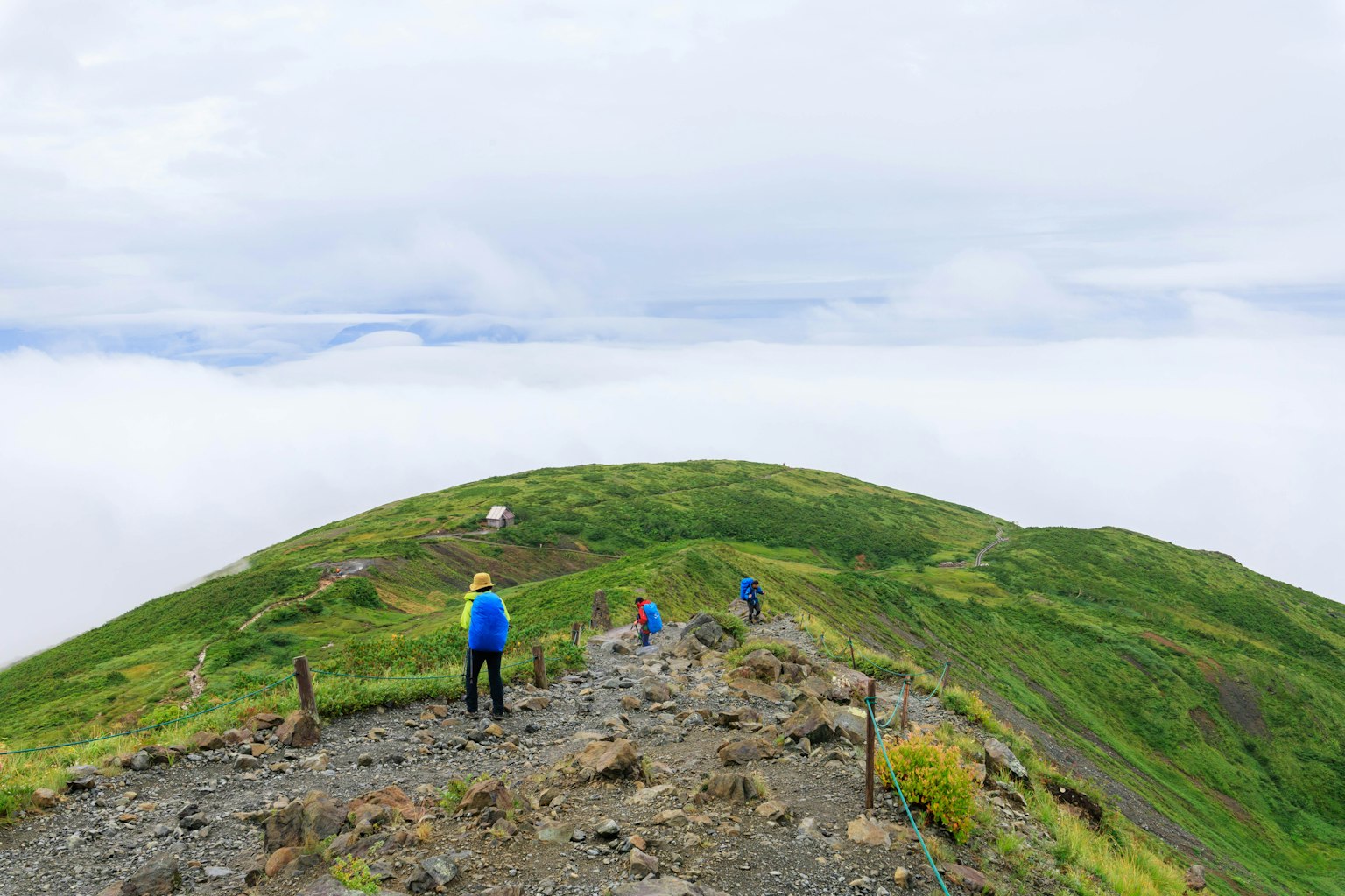 Pendaki di jalur gunung dengan lautan awan di bawah