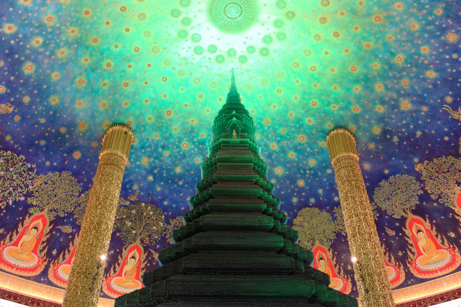 Estupa iluminada en verde con decoraciones de techo ornamentadas