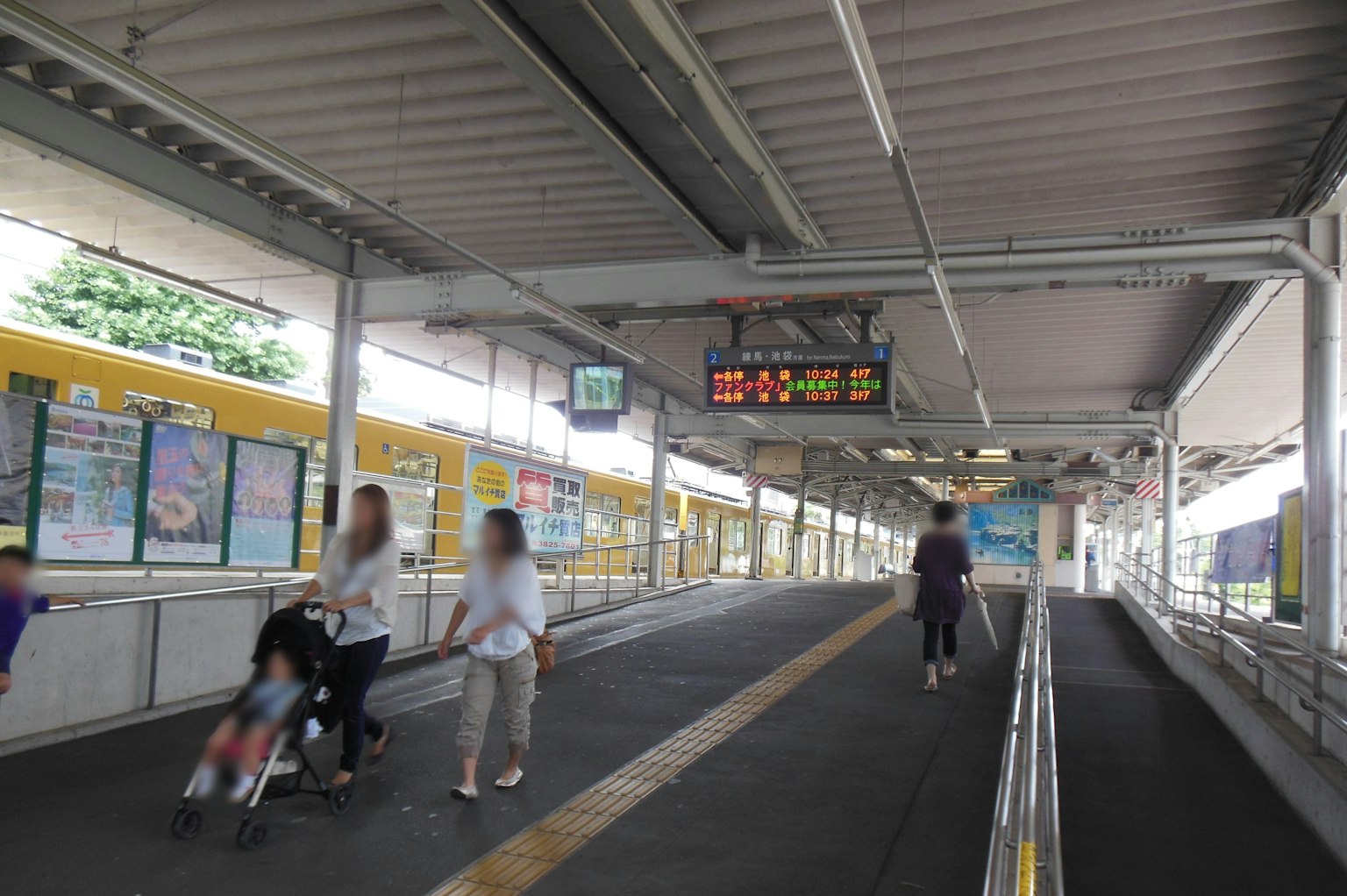Orang-orang di platform kereta dengan papan tampilan digital