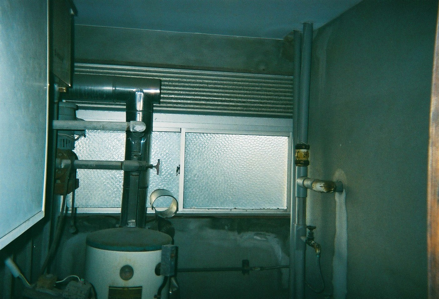 small utility room sink area with visible pipes and tank