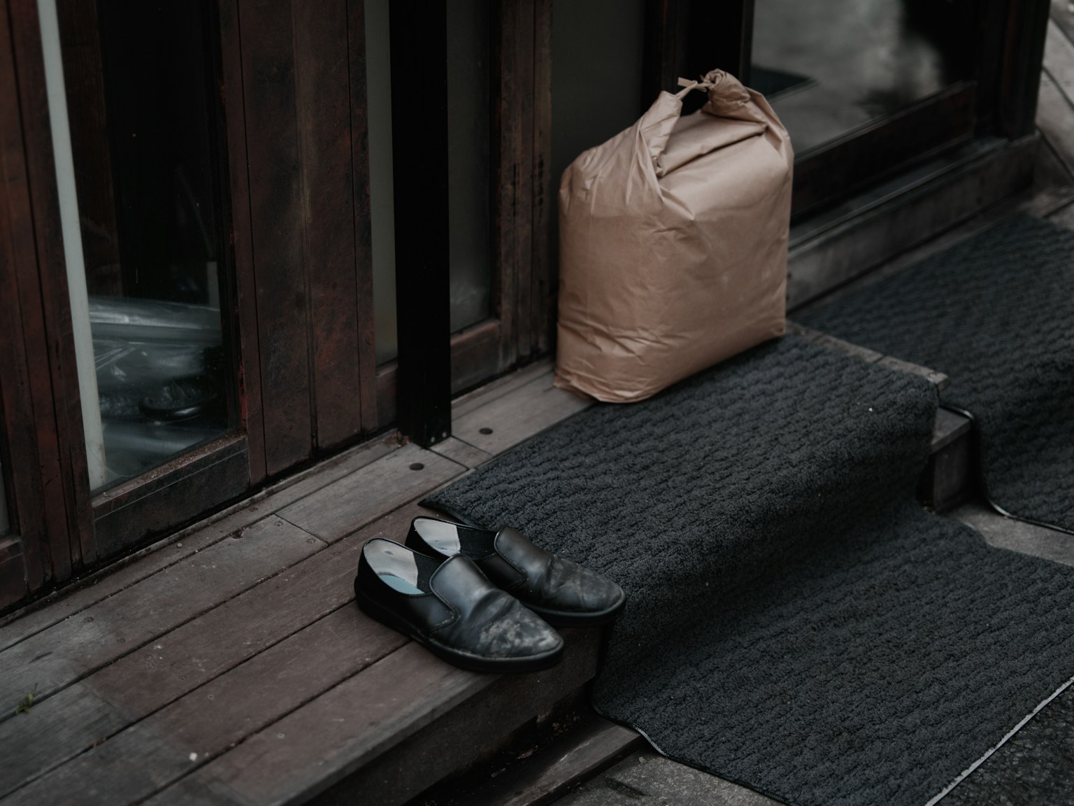 Scarpe nere e un pacco marrone posizionati all'ingresso