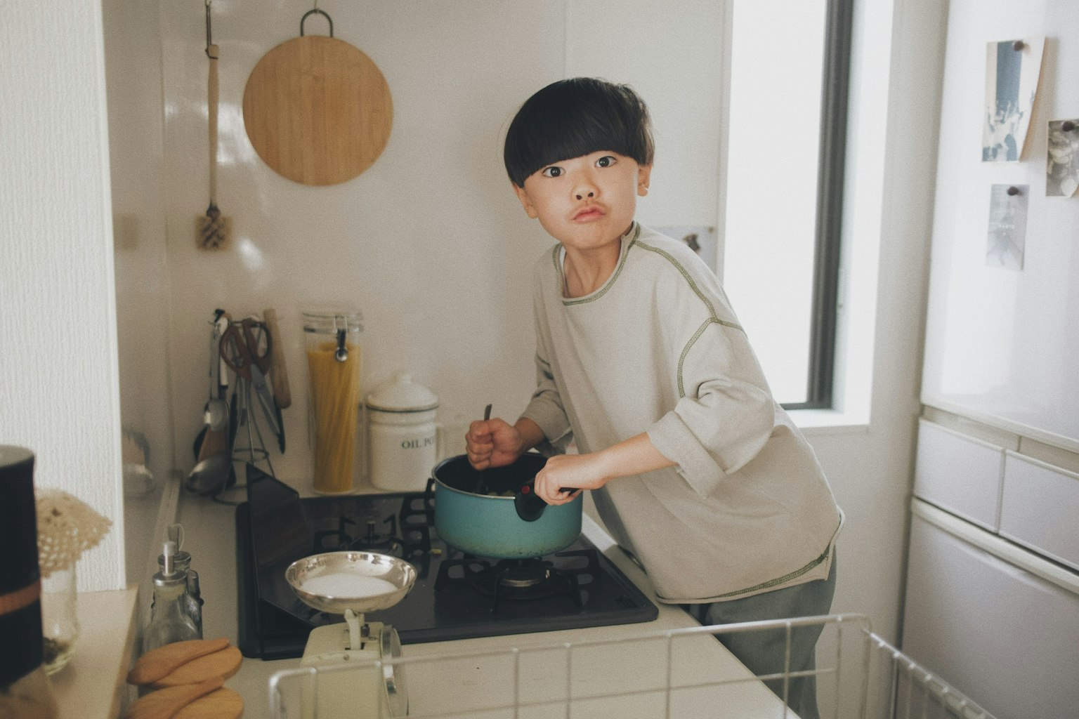 子供がキッチンで鍋をかき混ぜているシーン