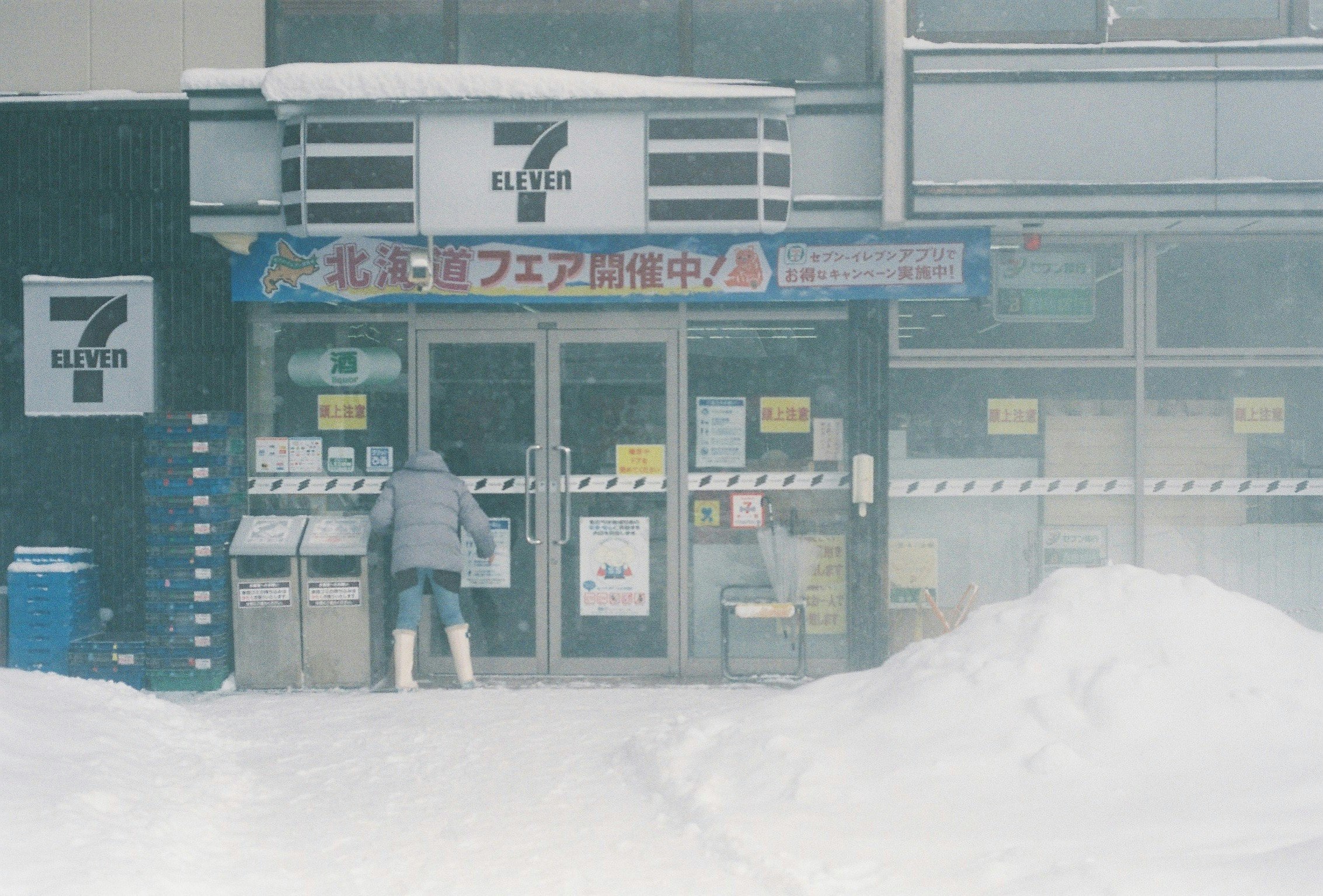 雪の中のコンビニ前の入口と看板
