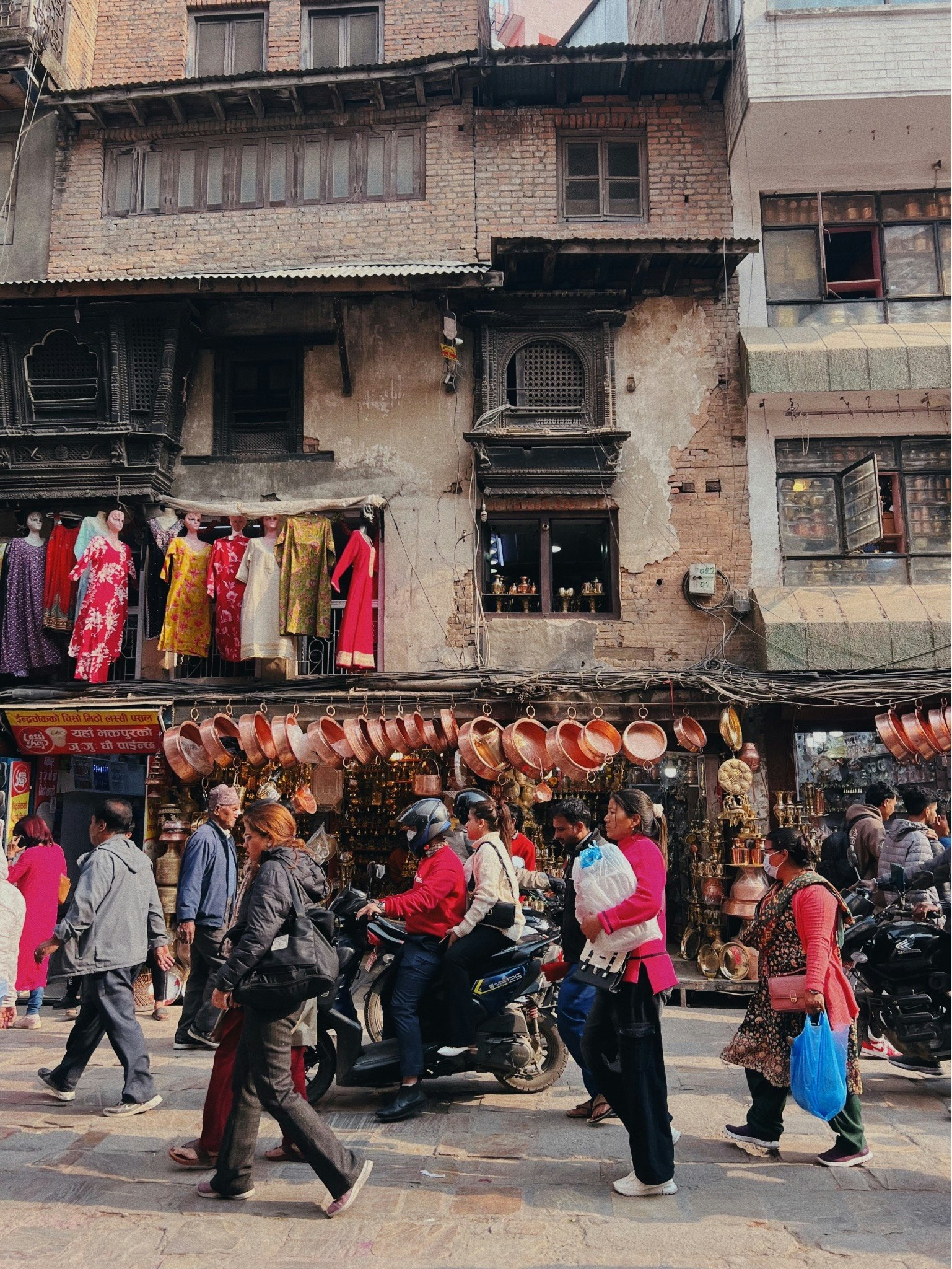 negozio di mercato in strada in Nepal con vestiti appesi e motociclette parcheggiate