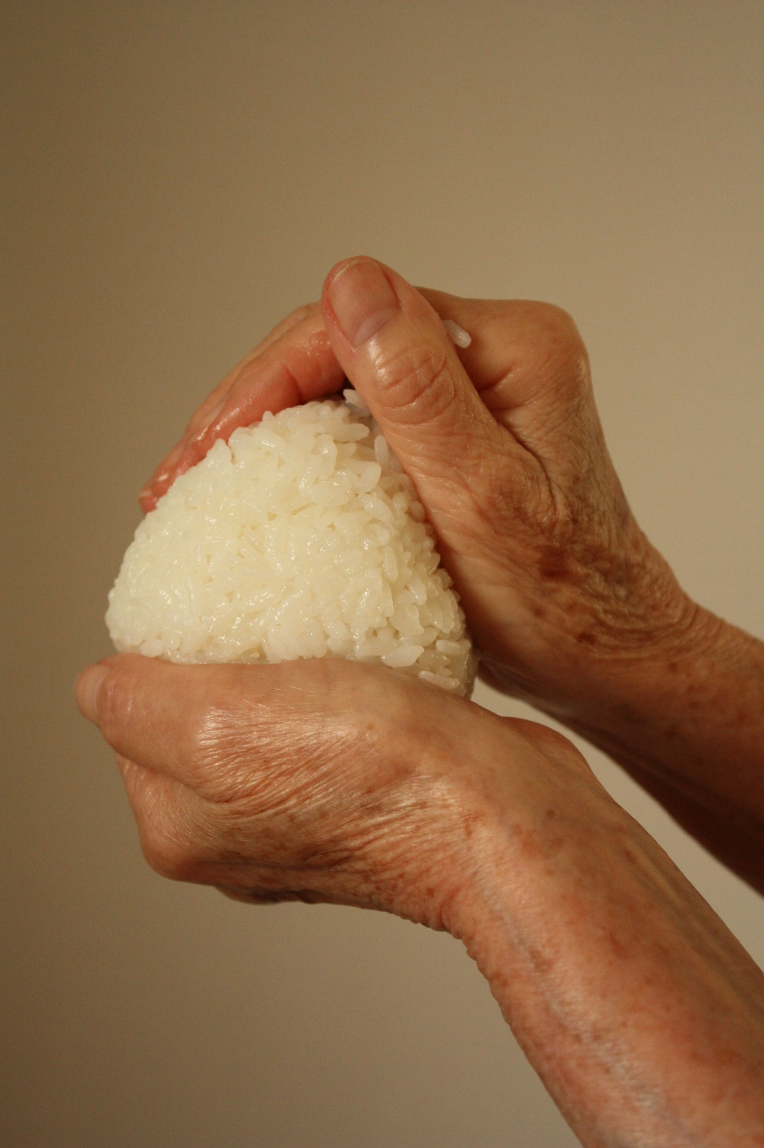 Mains d'une personne âgée formant une boule de riz