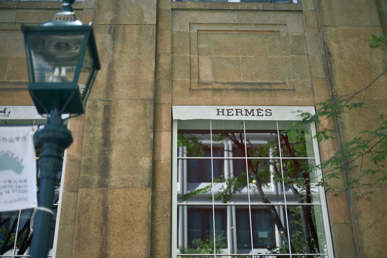 Esterno di un edificio con un'insegna Hermes e un lampione