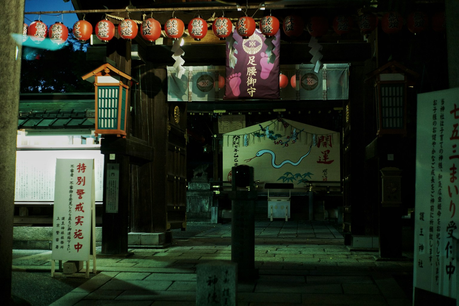 夜の神社の入り口にある提灯と看板