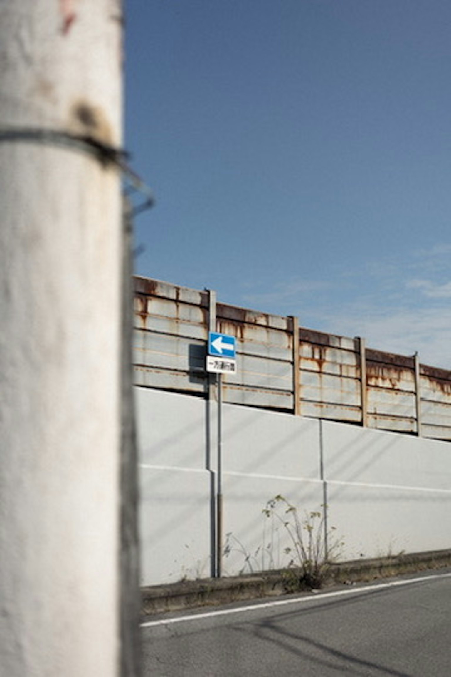 Blaues Richtungsschild an einer weißen Wand mit klarem blauen Himmel