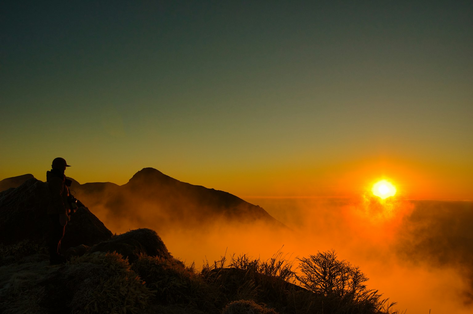 Alba sulle montagne con nebbia e silhouette di una persona