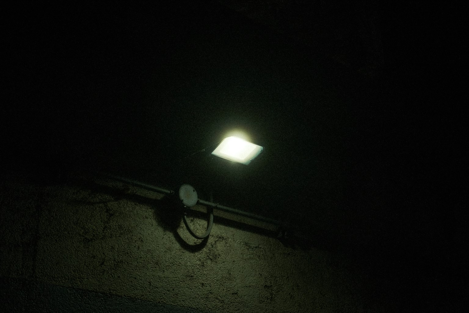 Luz brillante del techo contra un fondo oscuro con una pared vieja