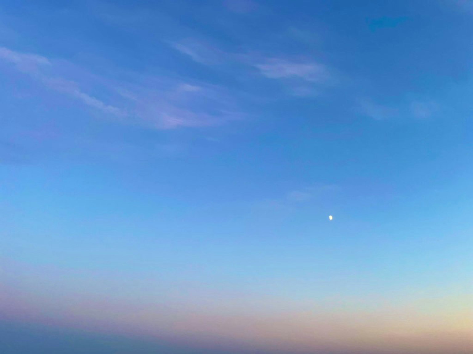寧靜的藍天，柔和的雲朵和一輪小月亮