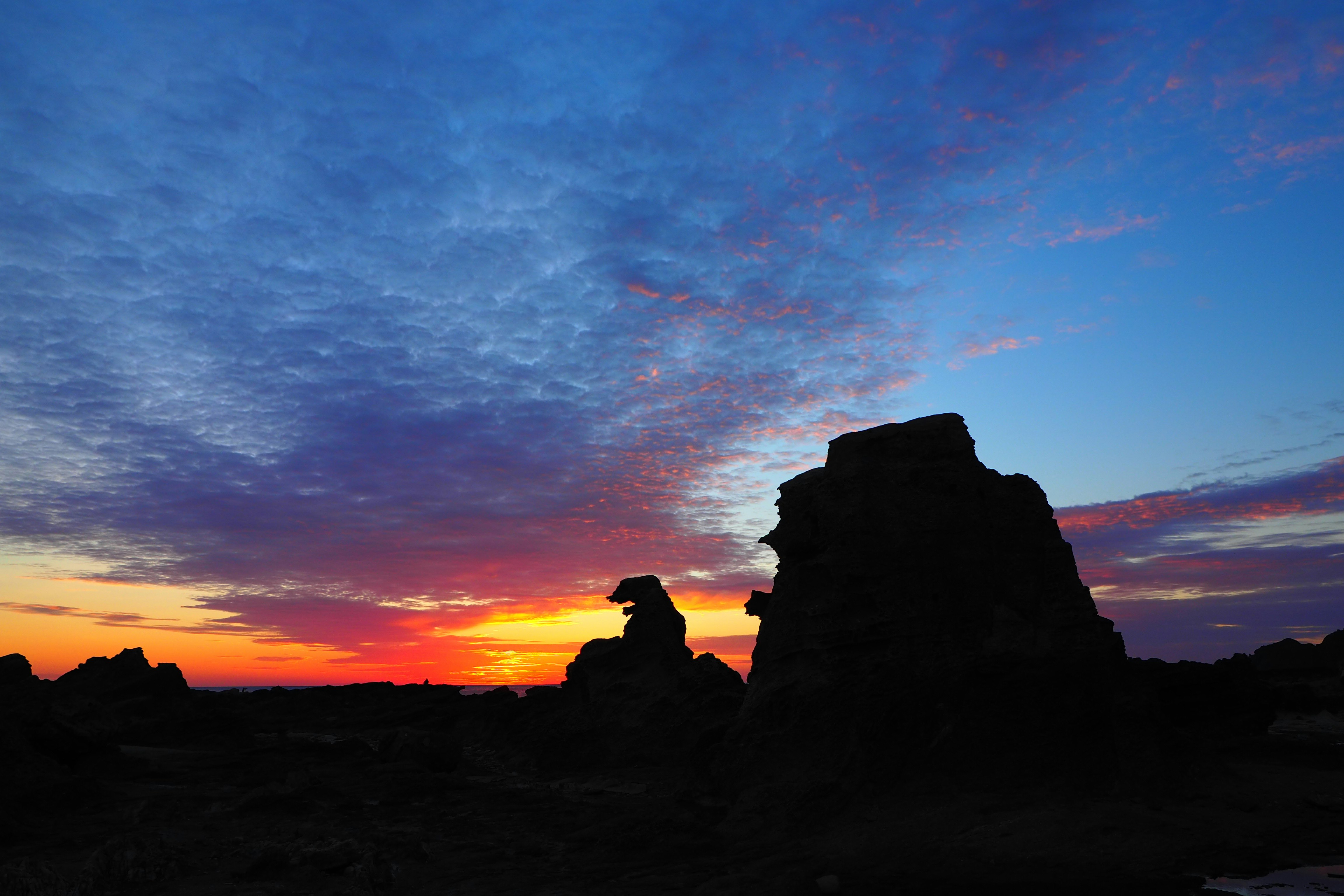 夕焼け空の下にそびえる岩のシルエット