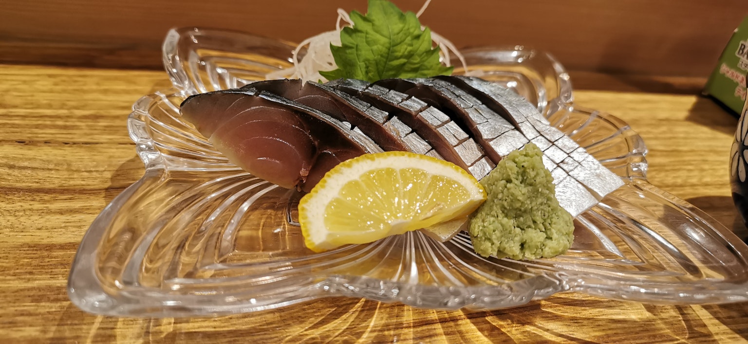 新鮮的生魚片放在盤子裡，旁邊有檸檬和芥末