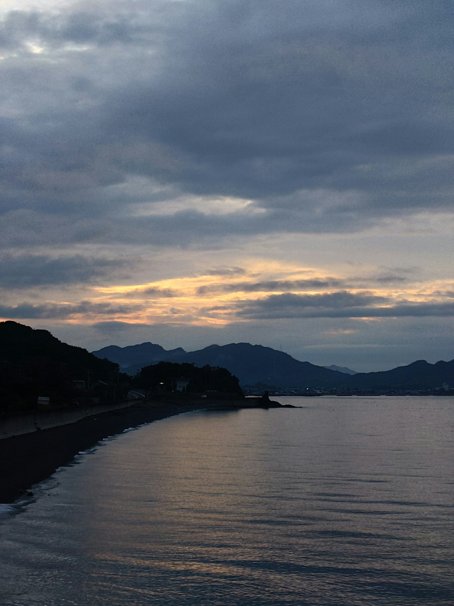 Paisaje costero al atardecer con montañas al fondo