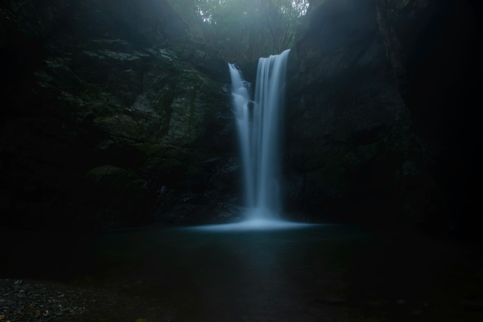Una hermosa cascada fluyendo en un entorno poco iluminado