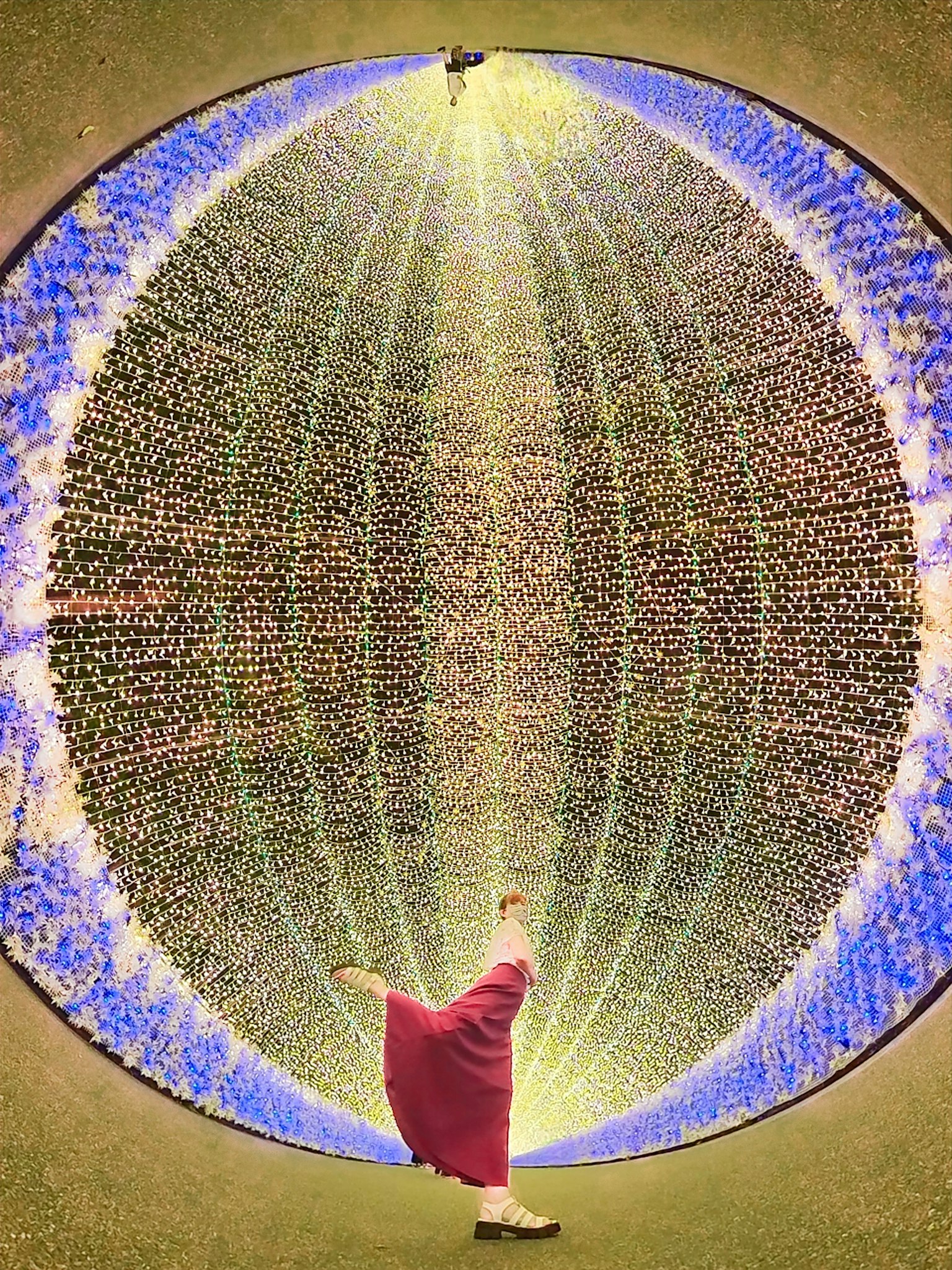 Une personne en tenue rouge se tenant dans un motif lumineux circulaire coloré