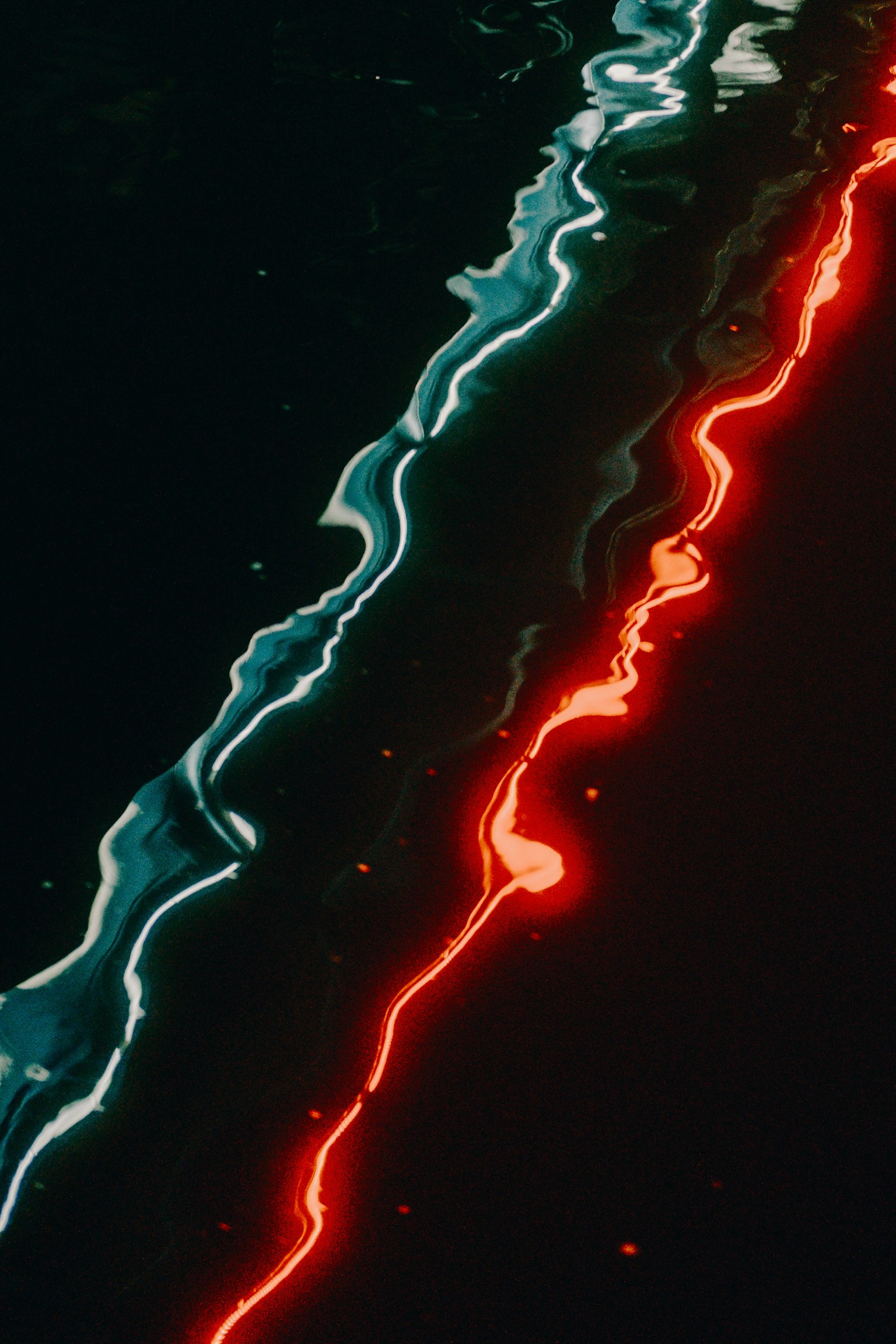 Reflets ondulés de lumière bleue et rouge sur une surface d'eau sombre