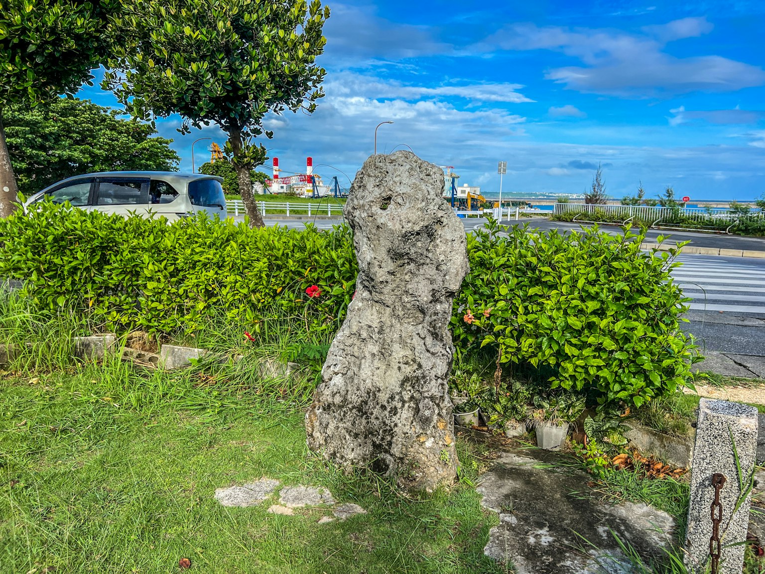 Große Steinskulptur umgeben von grünen Pflanzen und blauem Himmel