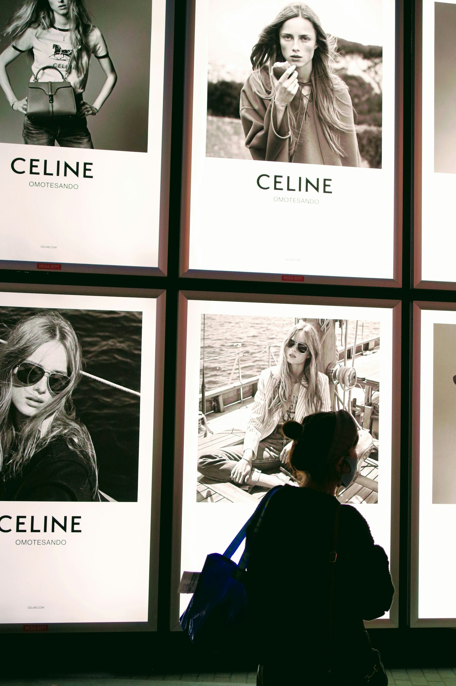 Eine Frau bewundert Celine-Werbung mit Schwarz-Weiß-Fashion-Porträts
