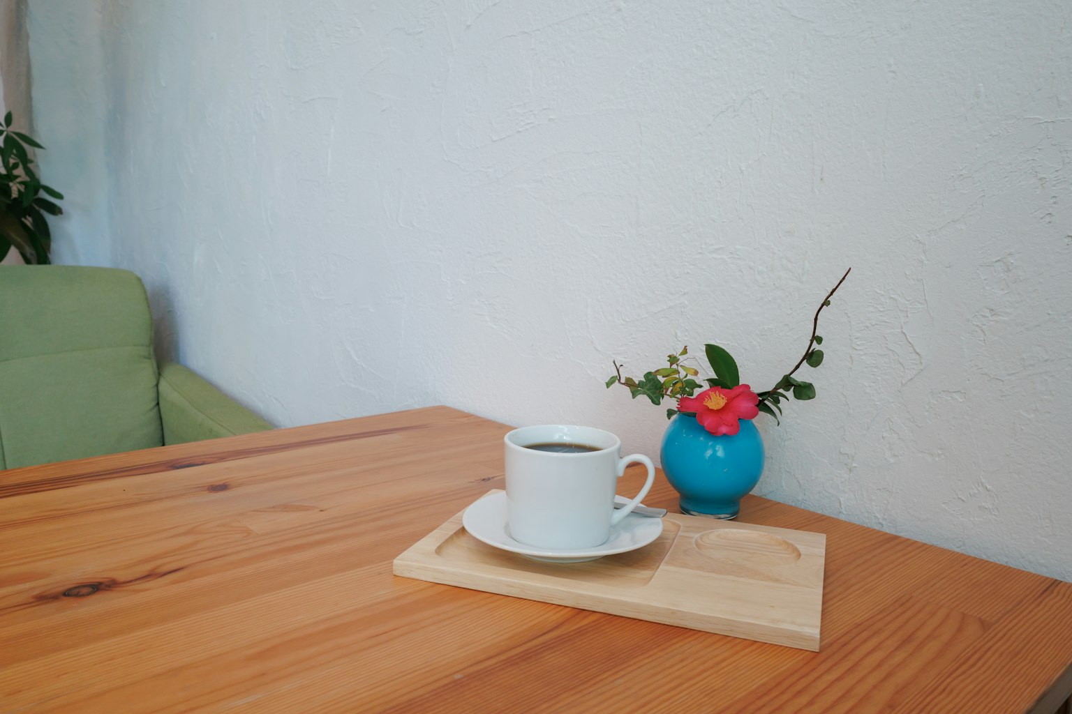 Tasse de café blanche sur une table en bois avec un vase bleu et des fleurs