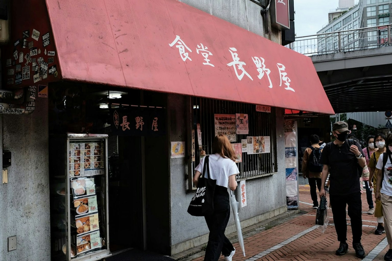 ภายนอกของร้าน Nagano-ya ที่มีหลังคาสีแดงผู้คนเดินผ่าน