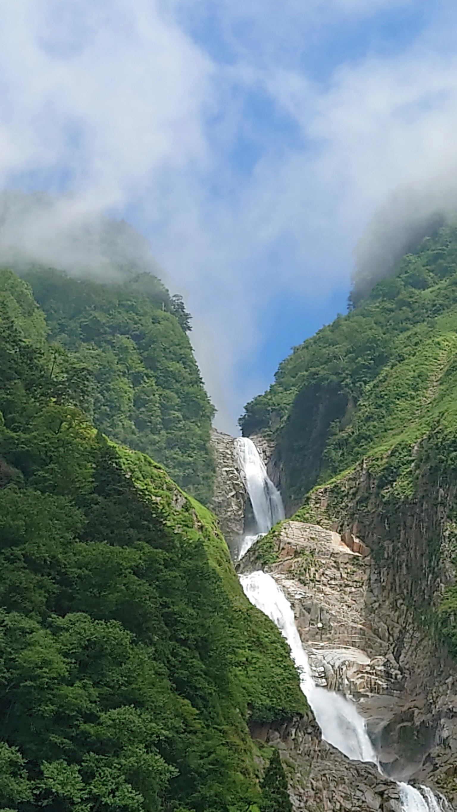 A stunning view of a waterfall cascading down surrounded by lush green mountains