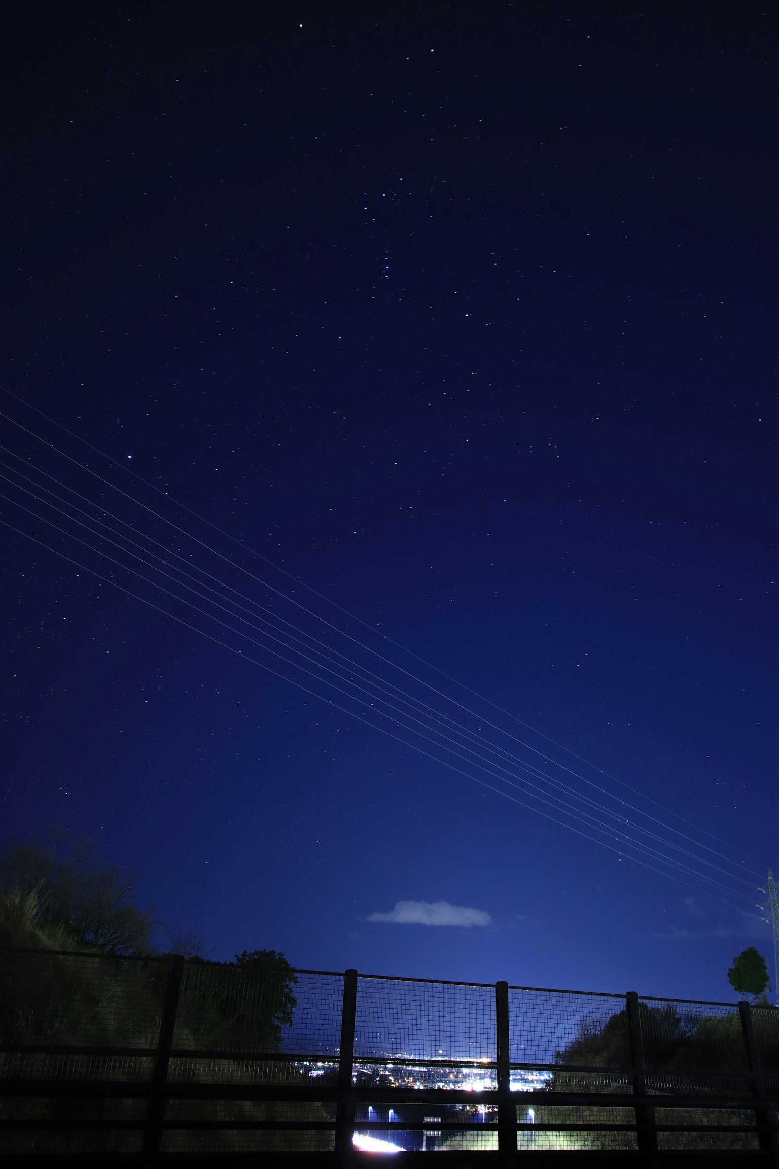 Cielo nocturno con estrellas brillantes y líneas eléctricas visibles