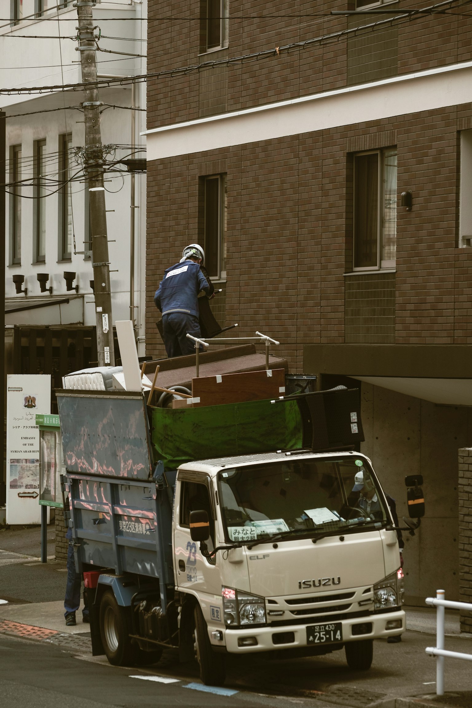 Un travailleur sur le toit d'un camion chargeant des meubles dans un environnement urbain