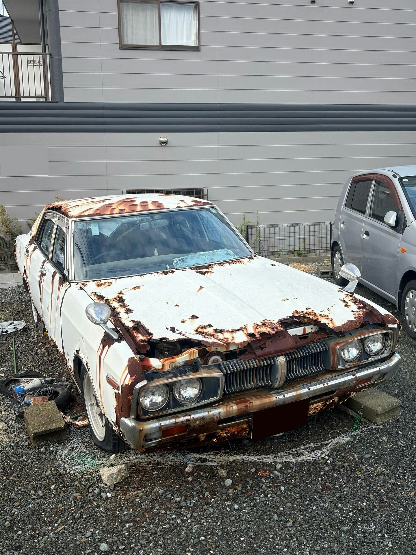 錆びた廃車のボンネットが剥がれた乗用車